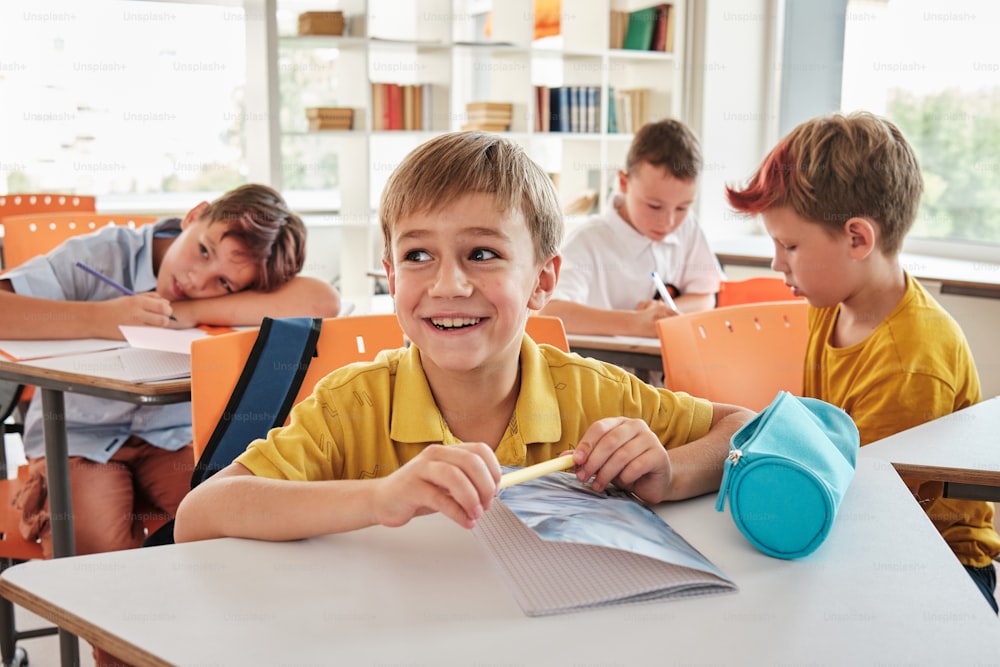 a young boy sitting at a table in a classroom