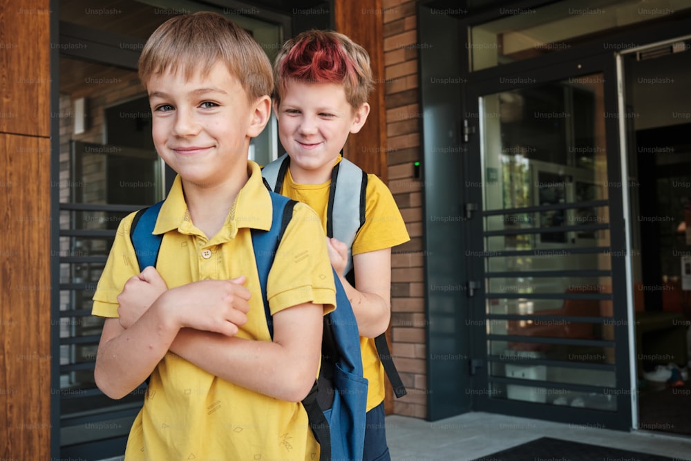 two young boys with backpacks standing in front of a building