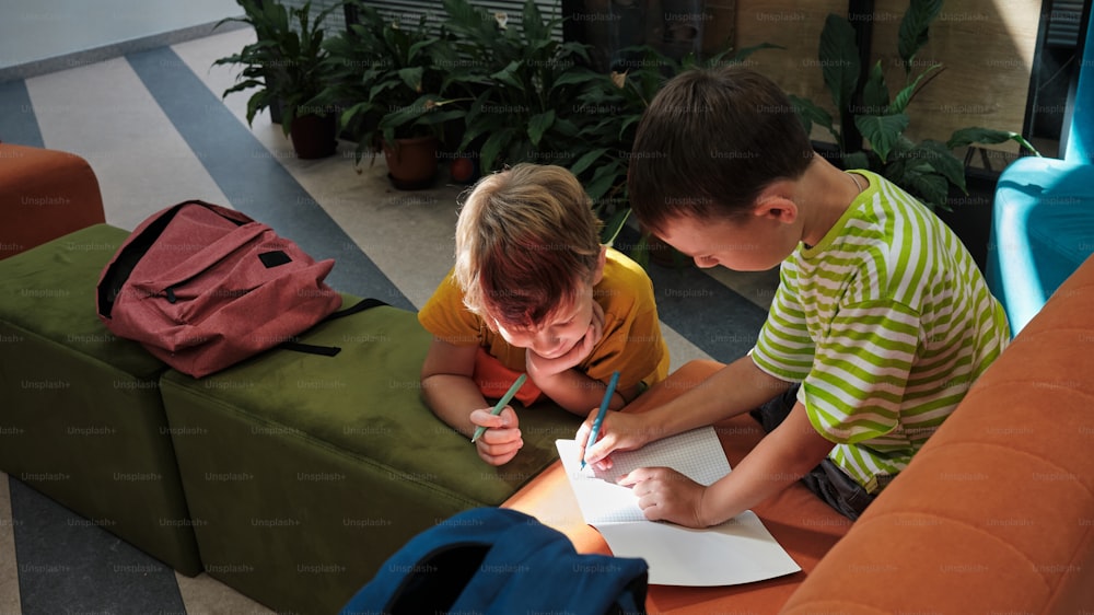 Un niño y un niño sentados en una mesa escribiendo en un pedazo de papel