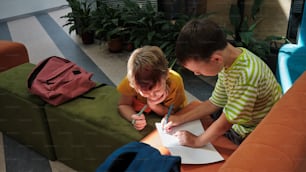 um menino e um menino sentados em uma mesa escrevendo em um pedaço de papel