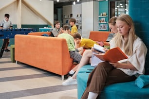 a woman sitting on a couch reading a book