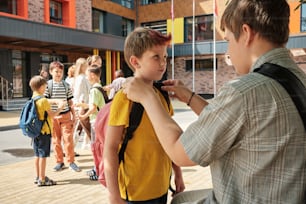 um homem ajudando um menino com sua mochila