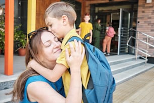 a woman holding a boy in her arms outside of a building