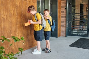 Dois meninos estão do lado de fora de um prédio