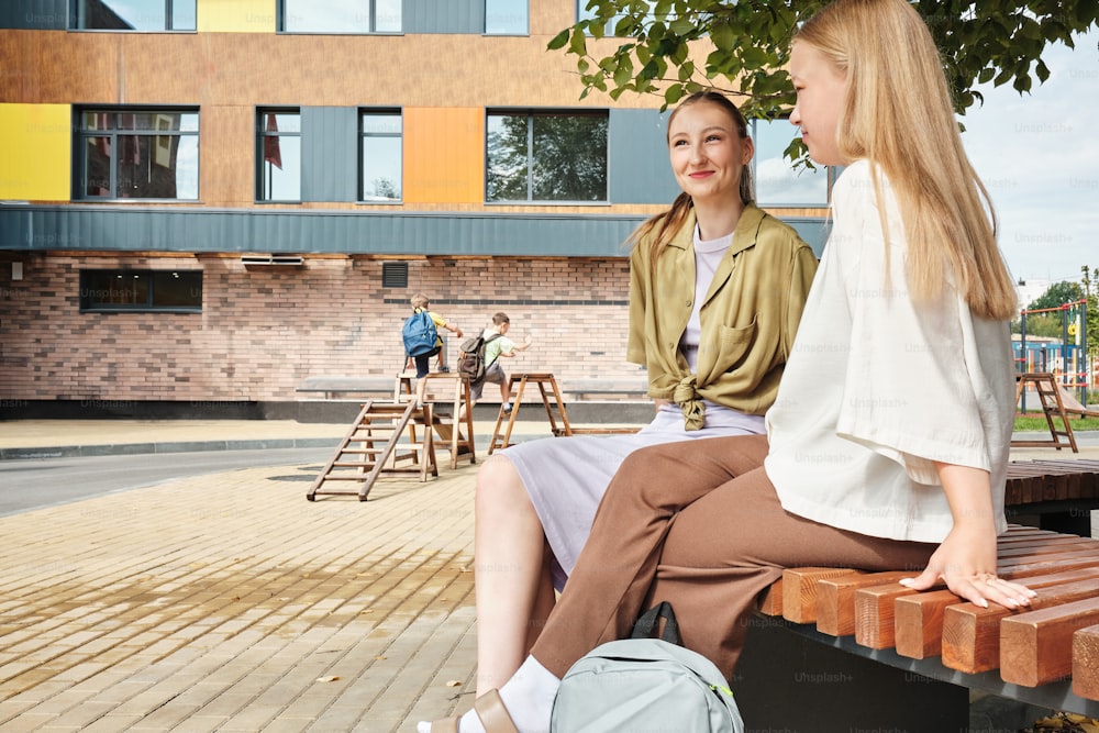 a couple of women sitting on top of a wooden bench
