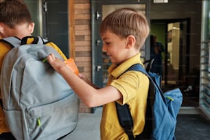 a boy in a yellow shirt and a boy in a blue backpack