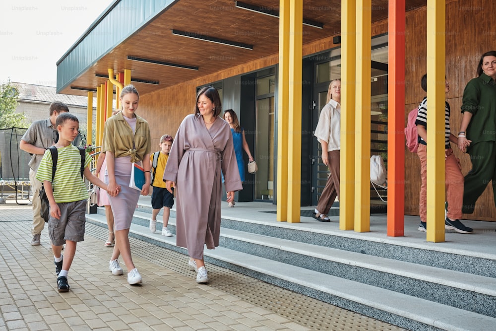 a group of people walking down a sidewalk next to a building