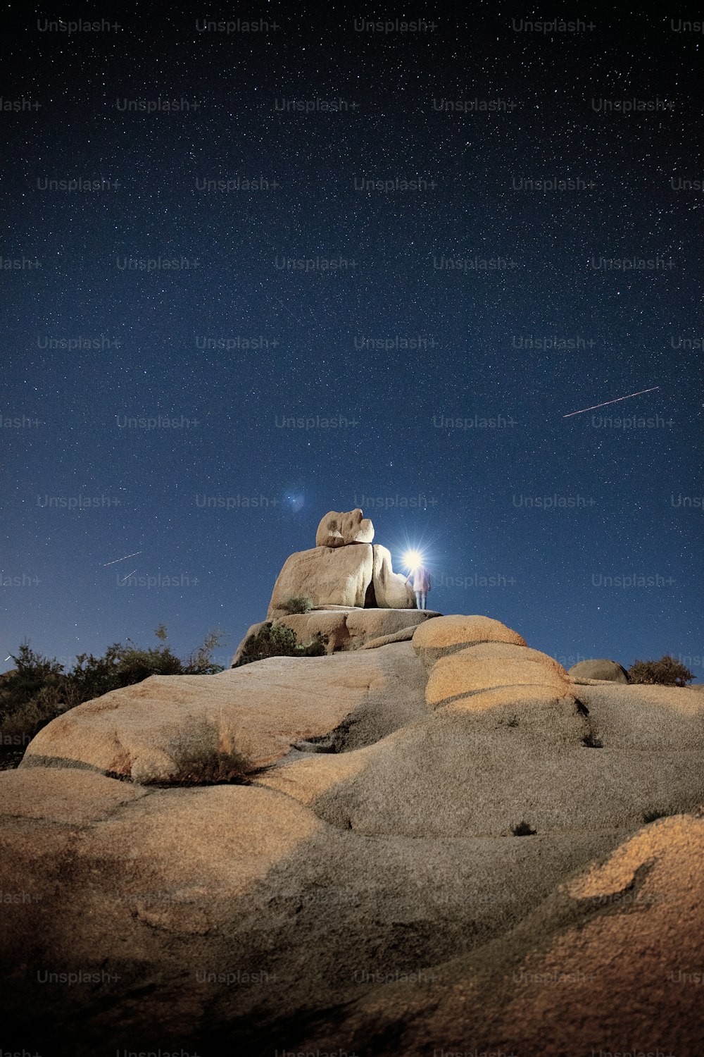 a couple of people standing on top of a large rock