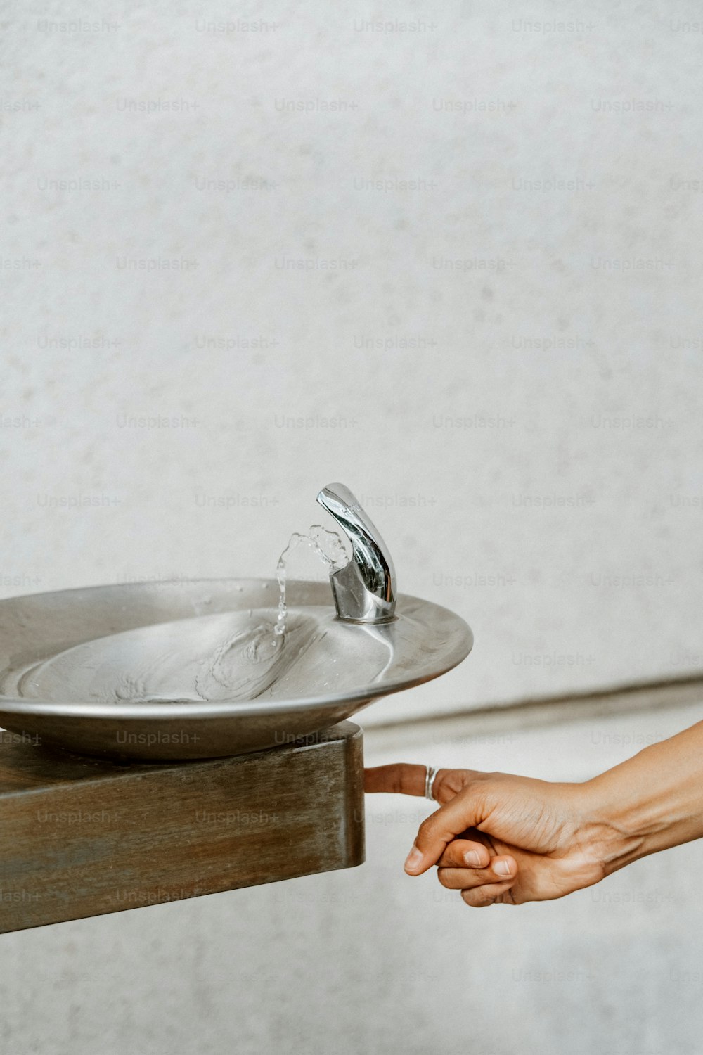 a person's hand reaching for a water fountain
