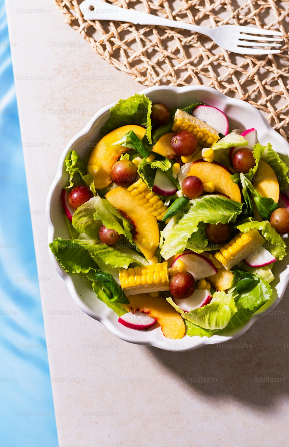 a bowl of fruit salad next to a fork and knife