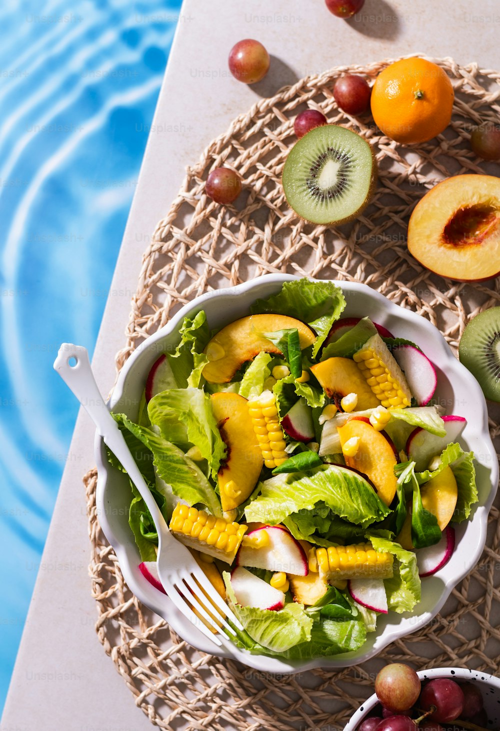 uma tigela de salada de frutas ao lado de uma piscina