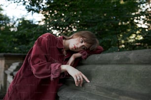 a woman leaning against a stone wall with her hand on her face