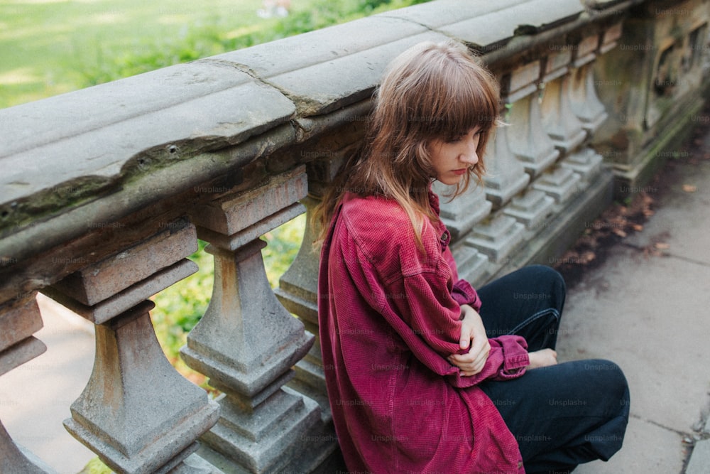 uma jovem sentada em um banco de pedra