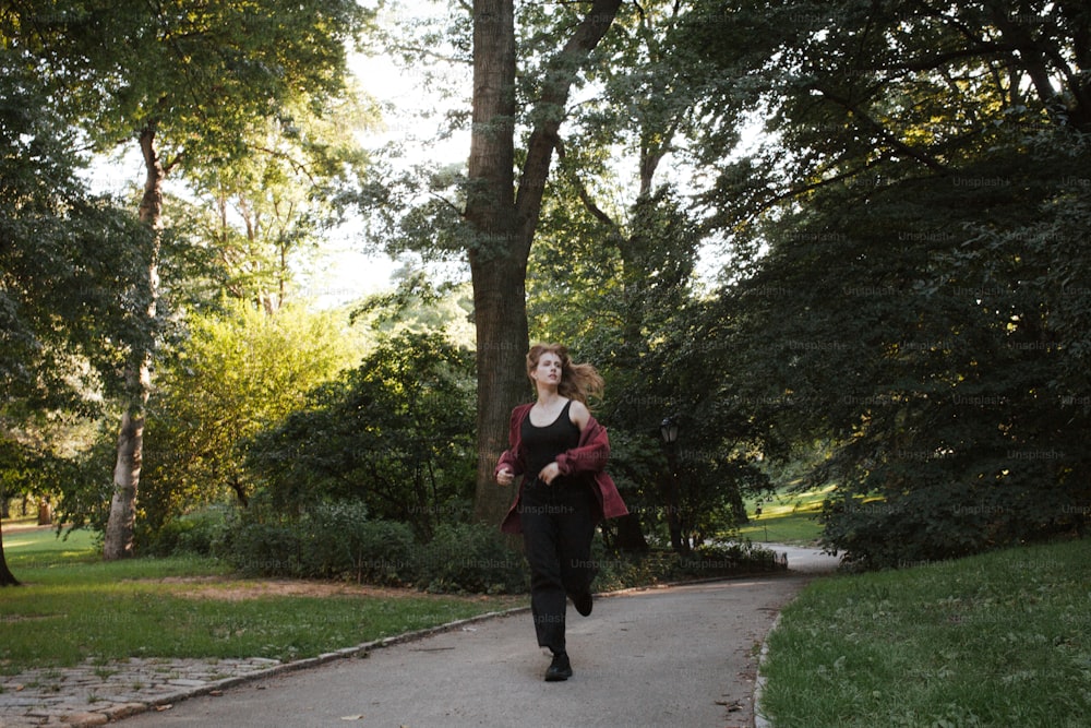 uma mulher caminhando por um caminho em um parque