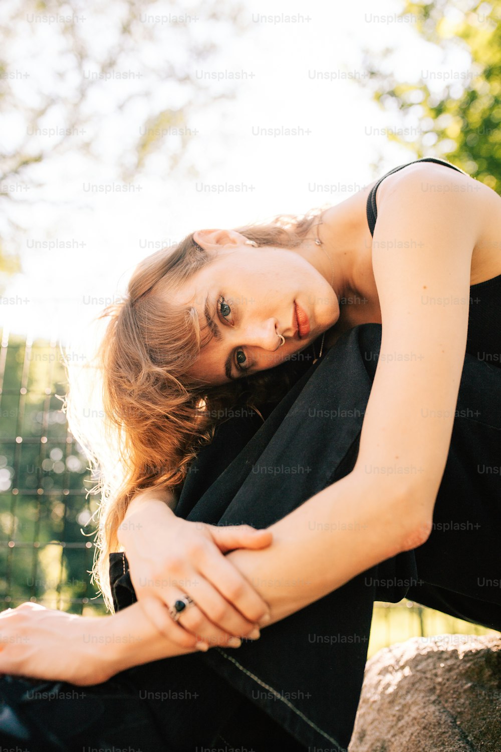 a woman sitting on a rock with her arms crossed