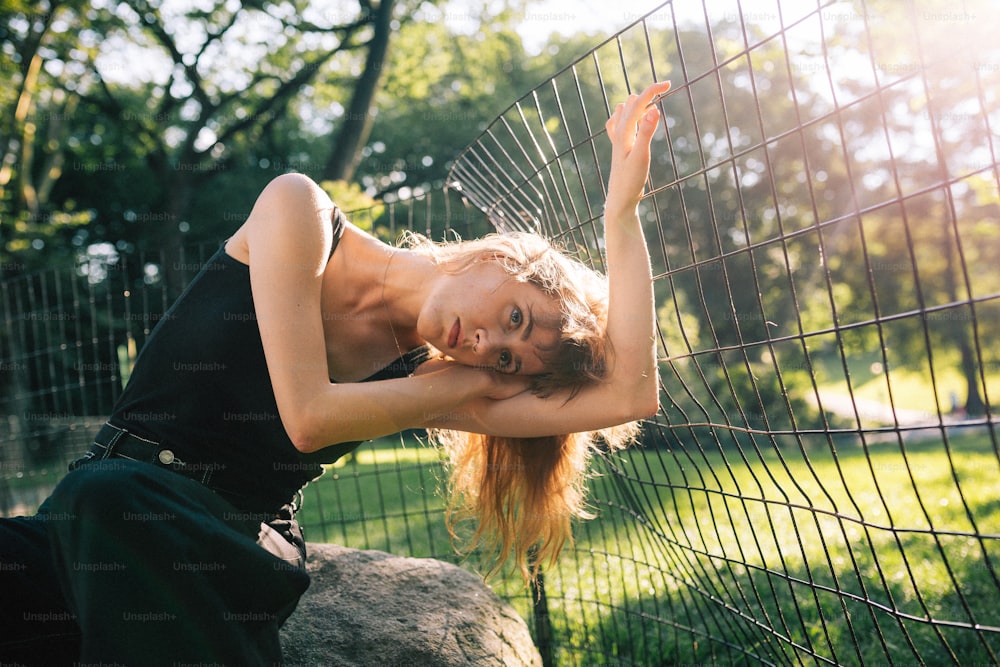 a beautiful young woman leaning against a fence