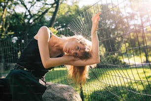 a beautiful young woman leaning against a fence