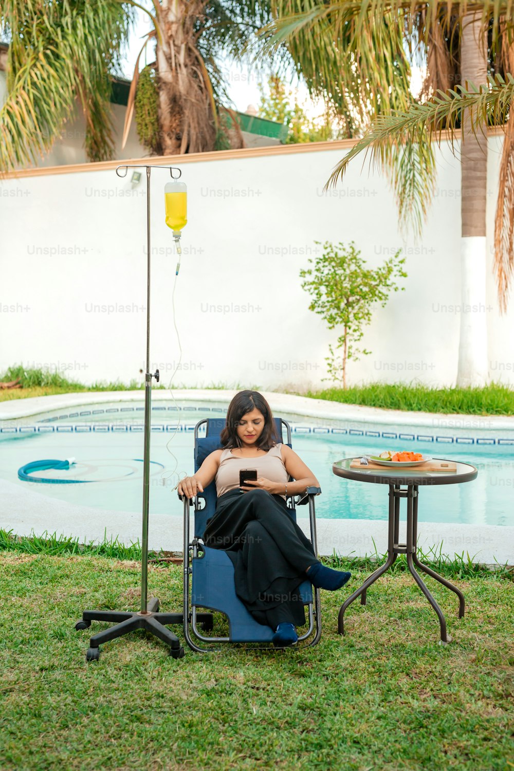 a woman sitting in a chair next to a pool