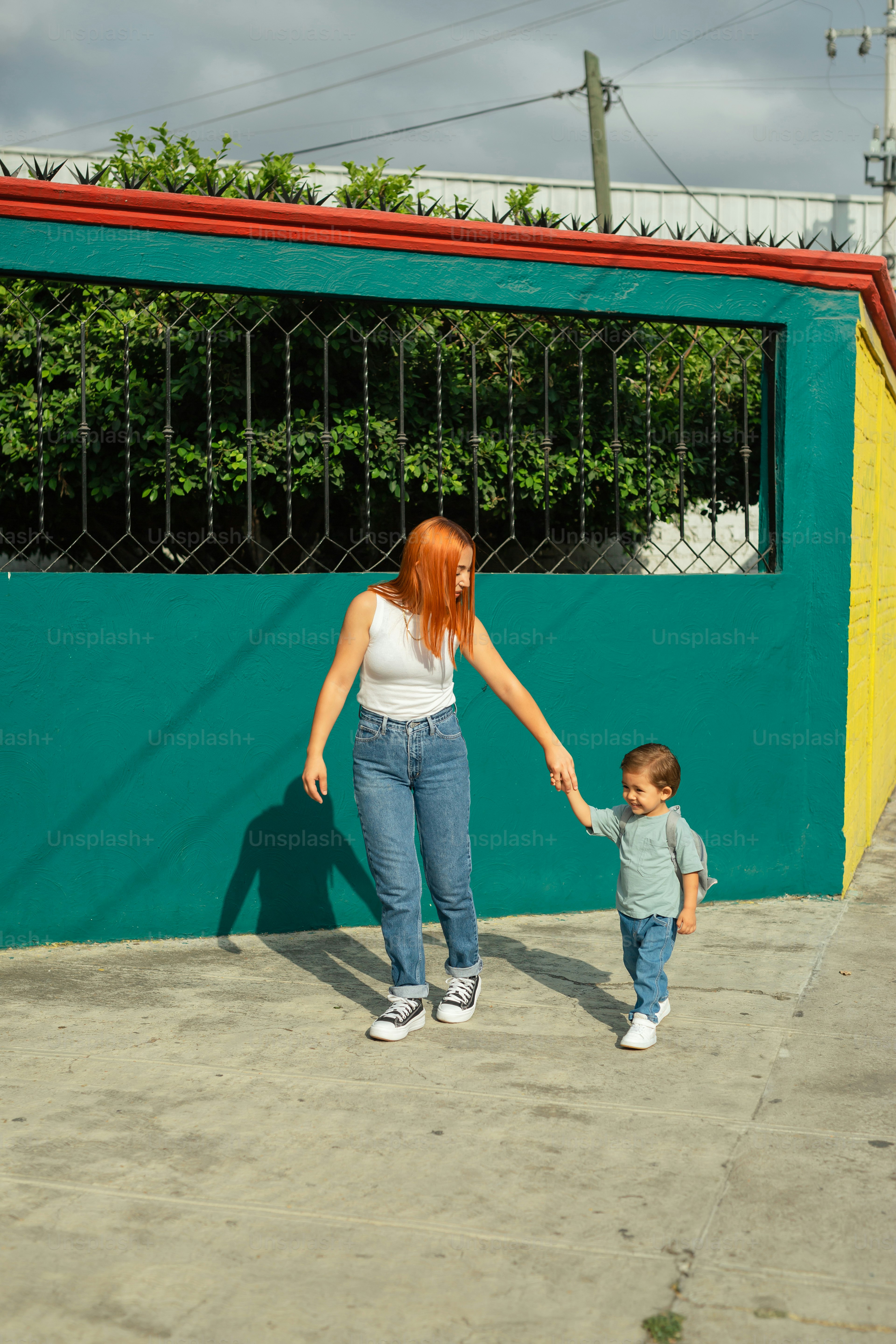 a woman holding the hand of a small child