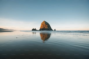 a large rock sitting on top of a beach next to the ocean