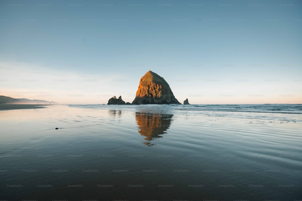 Una grande roccia seduta sulla cima di una spiaggia vicino all'oceano