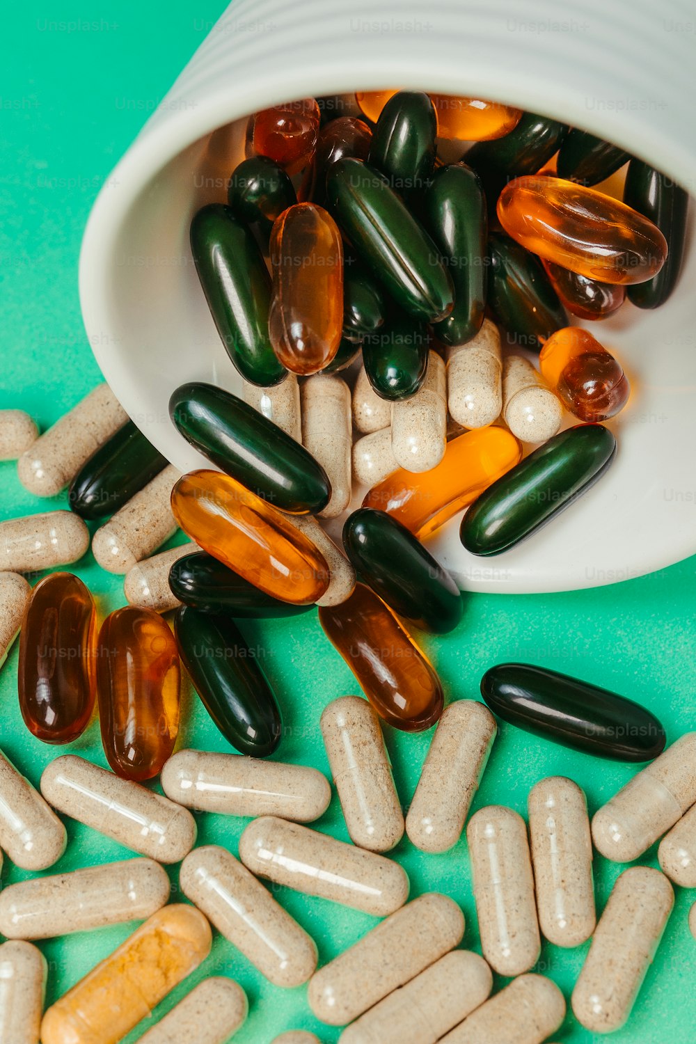 pills spilling out of a white container onto a green surface