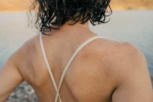 a person with wet hair standing by a body of water