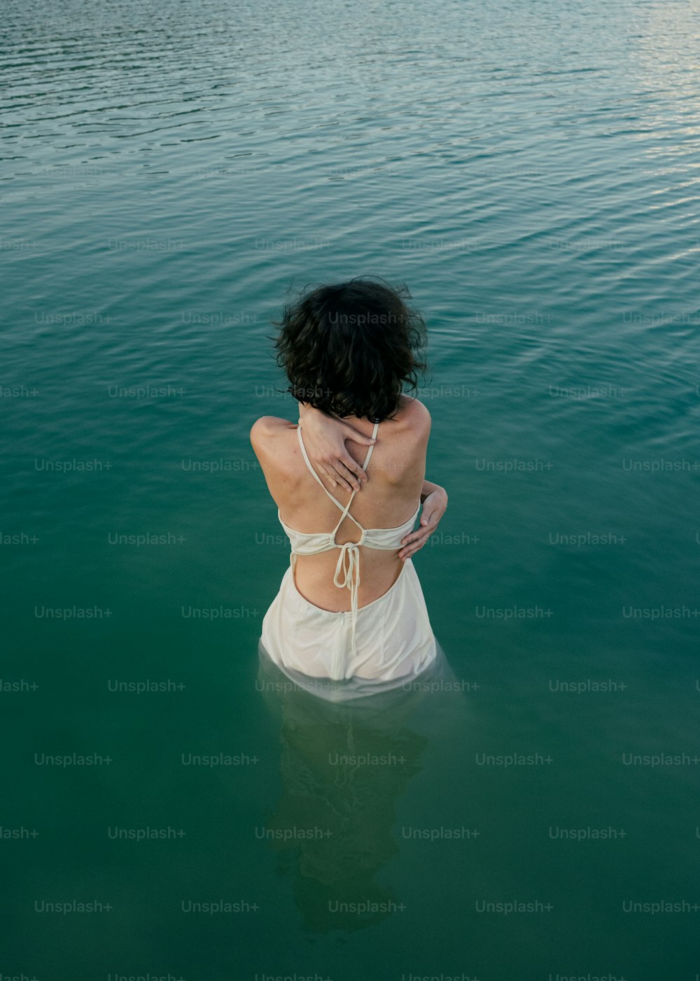 a woman in a white dress sitting in the water
