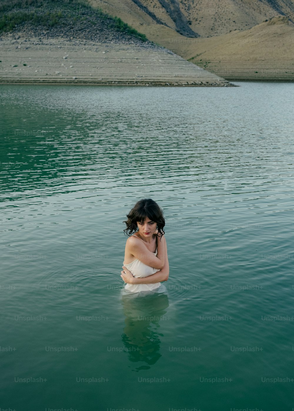 uma mulher em um vestido branco sentado em um corpo de água