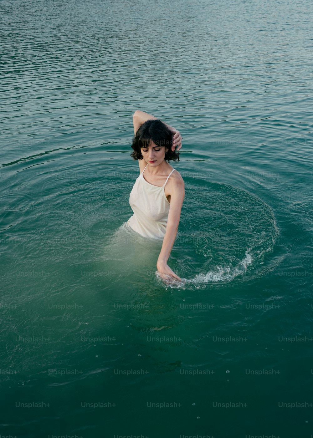 Une femme dans un plan d’eau vêtue d’une robe blanche