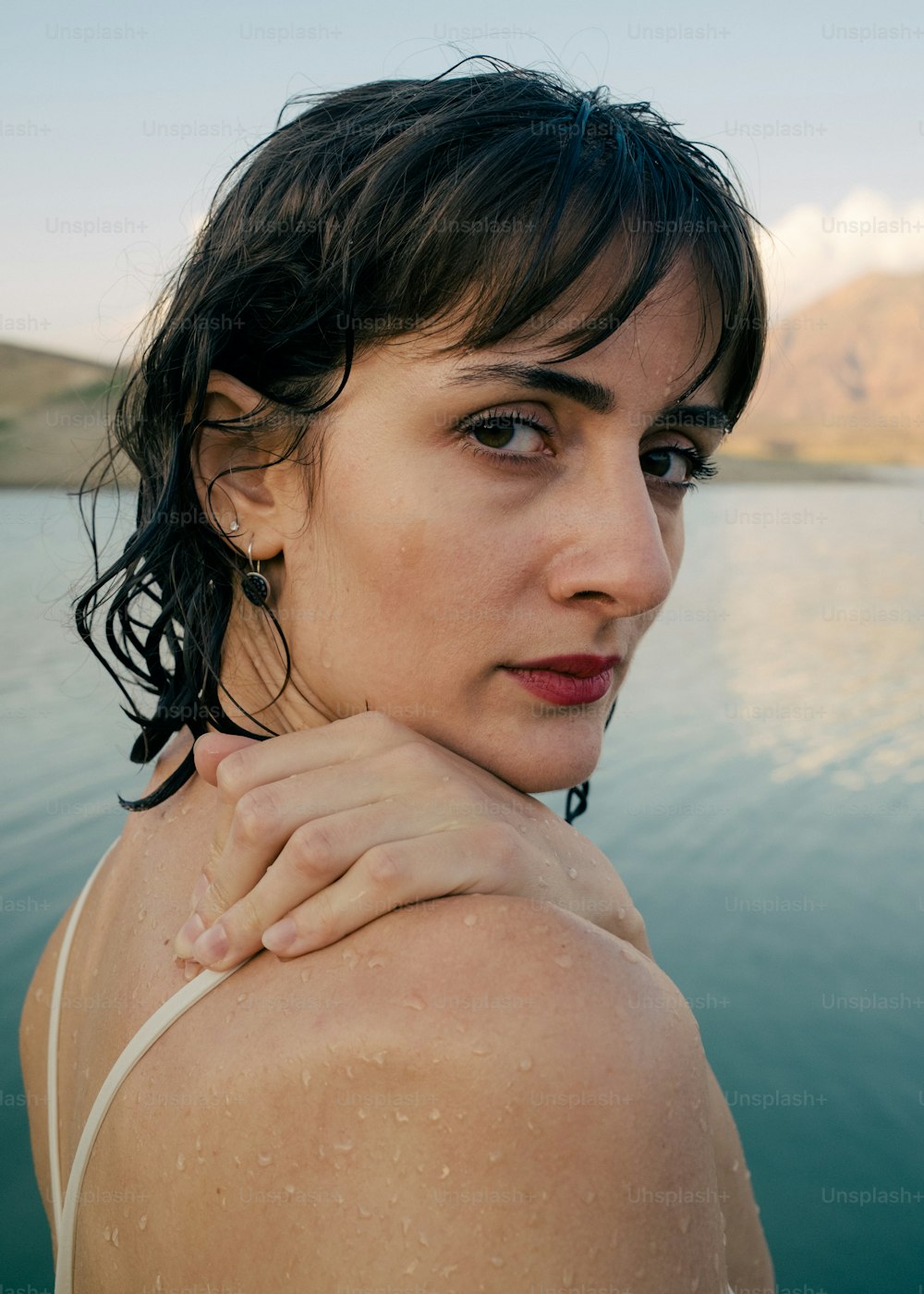 a woman standing in the water with her arm around her neck