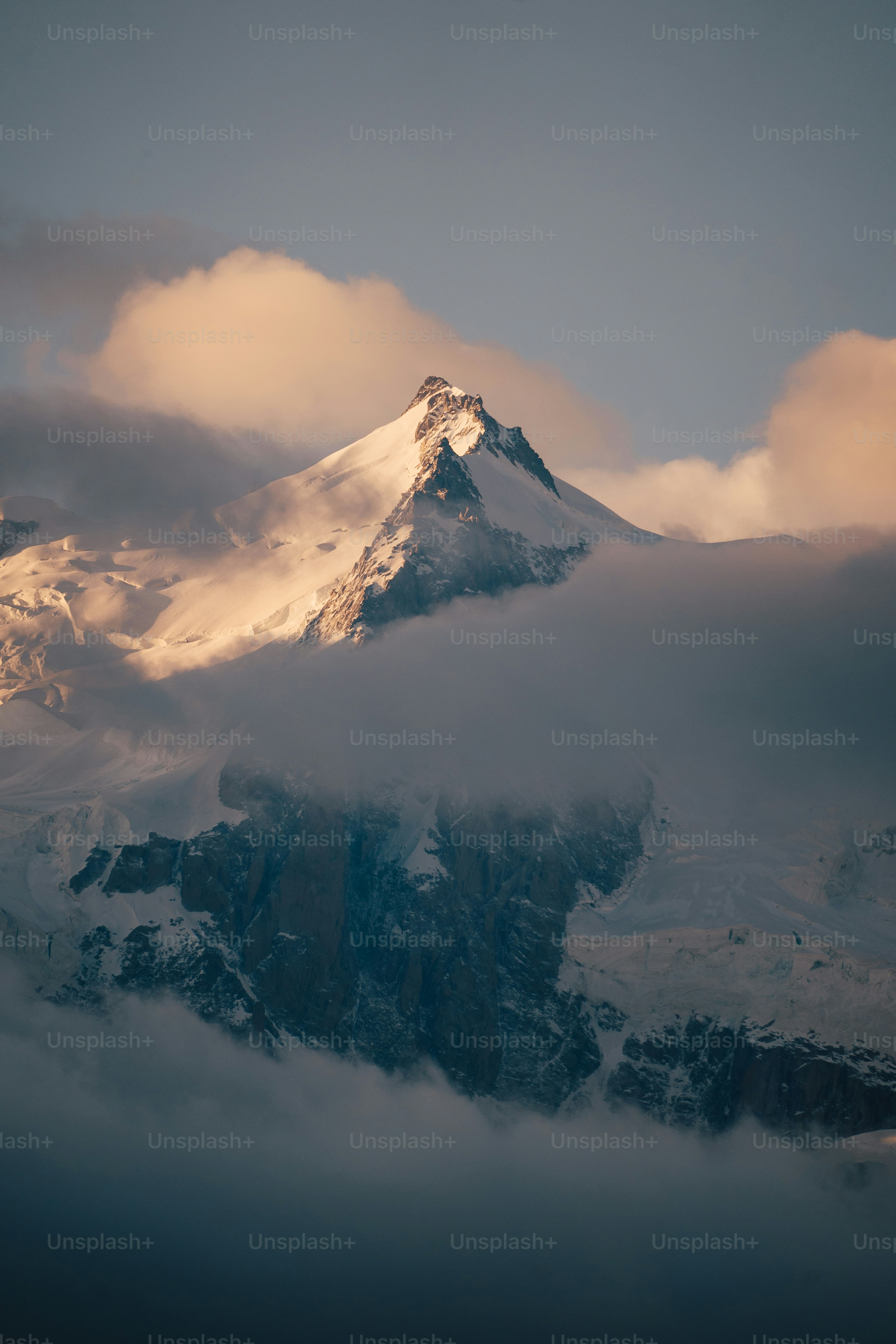a snow covered mountain with clouds in the foreground