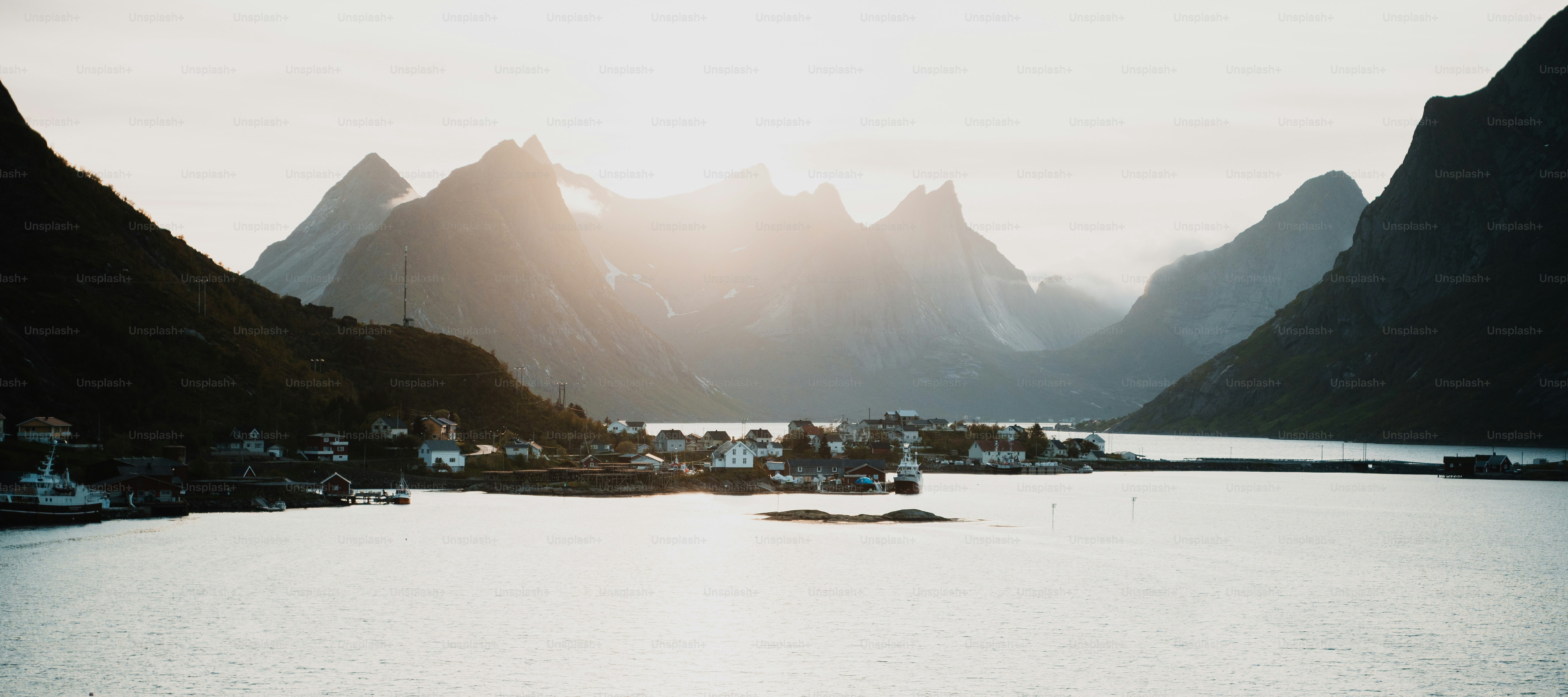 the sun is setting over a small village on the water
