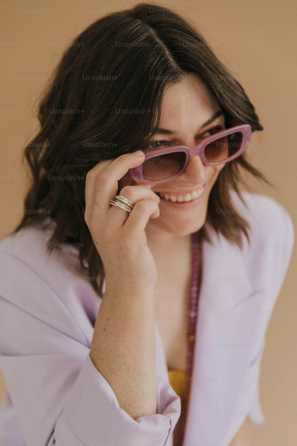 uma mulher de camisa roxa segurando um par de óculos escuros
