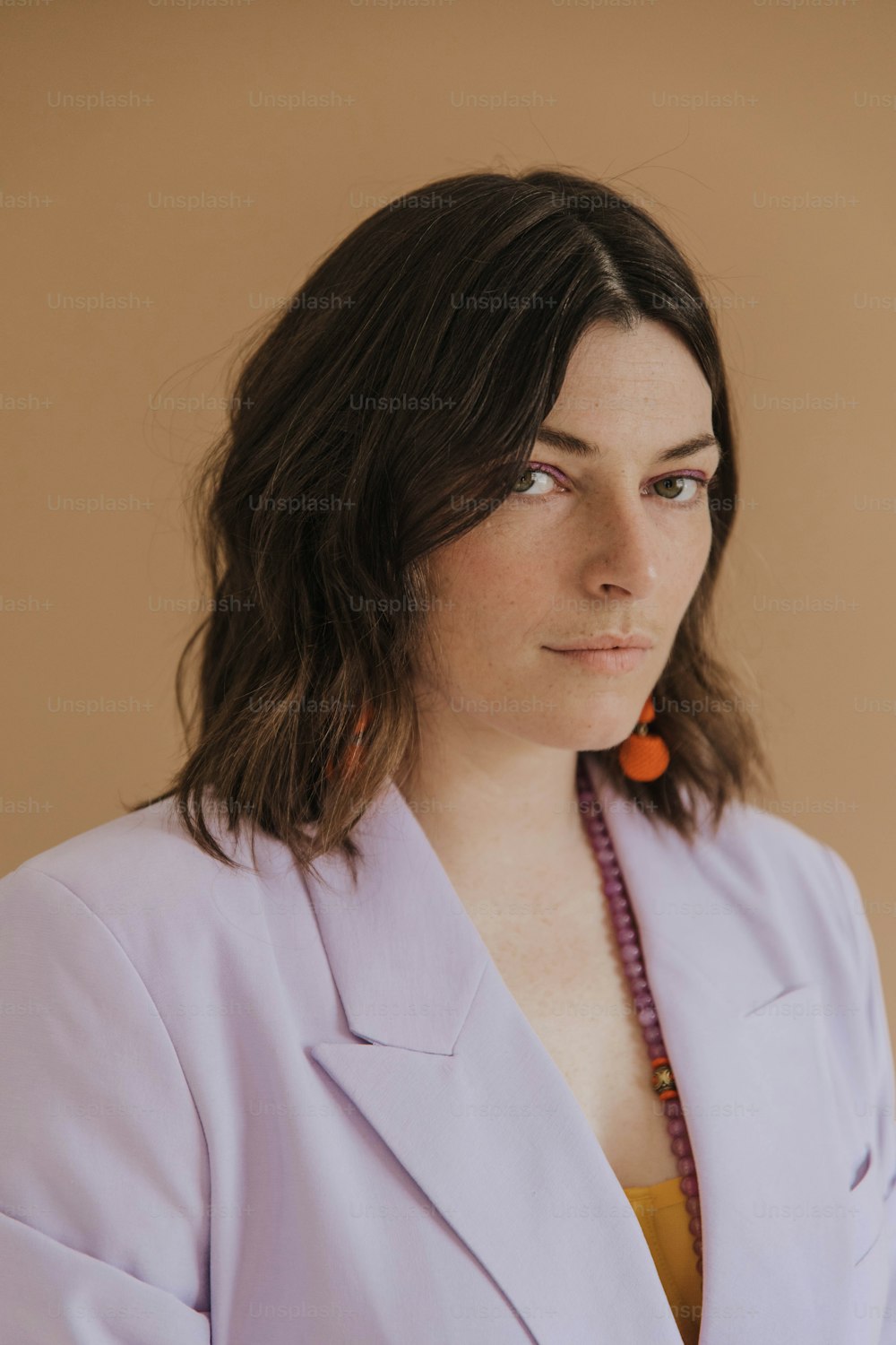 a woman wearing a purple jacket and a beaded necklace