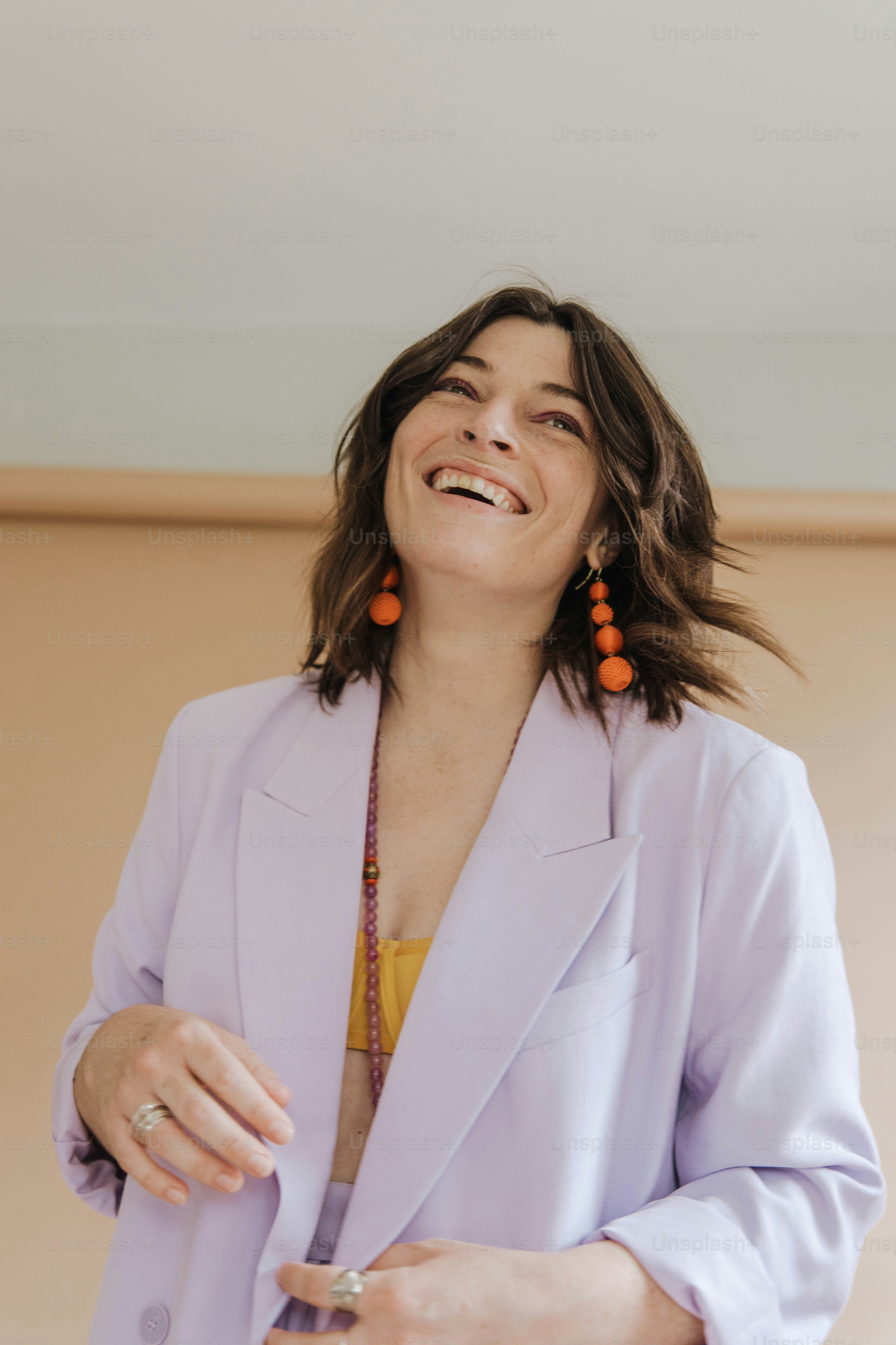a woman in a purple blazer and orange earrings