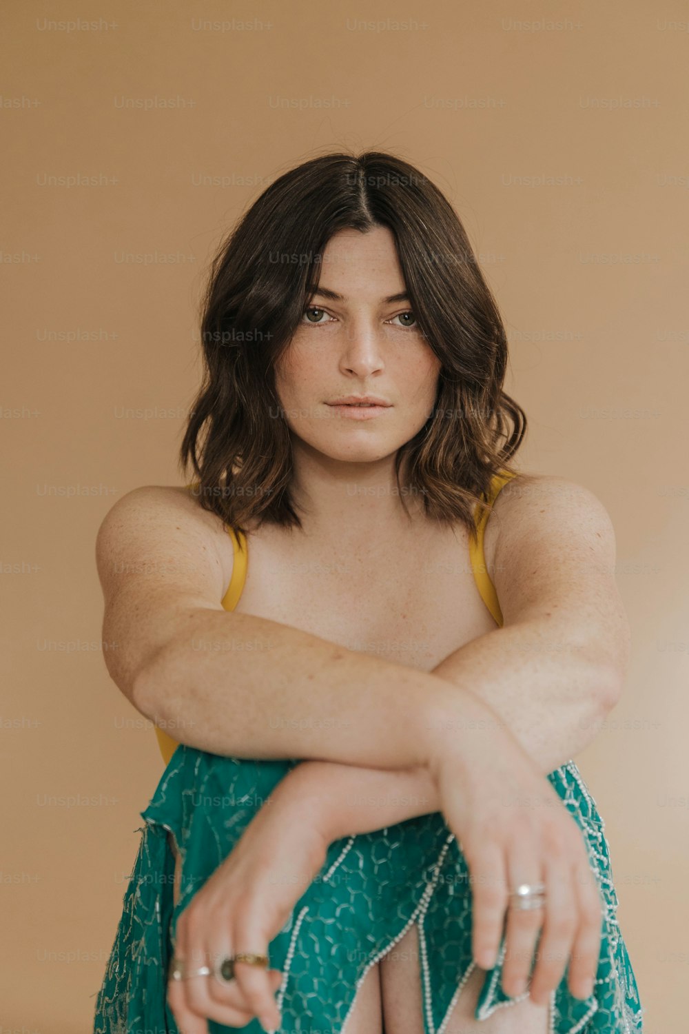 a woman in a green dress sitting on a stool