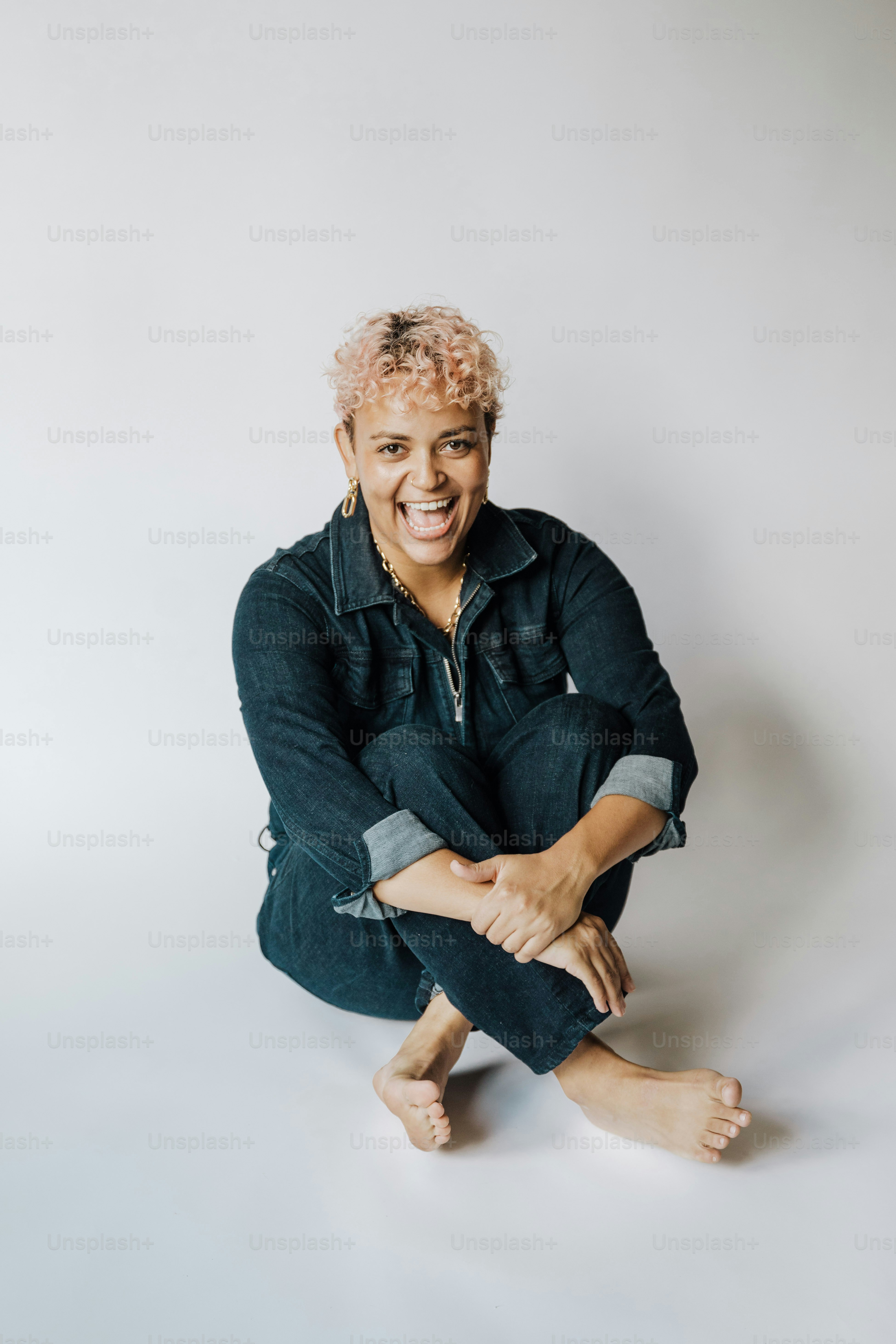 Une femme souriante assise par terre, les jambes croisées