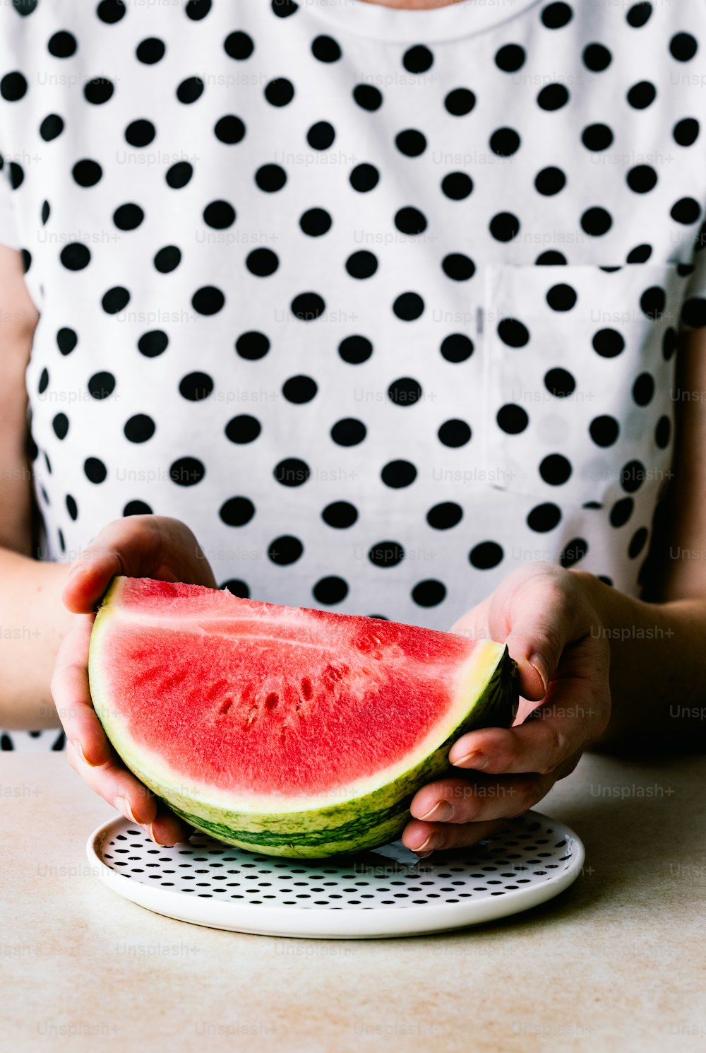 a woman holding a slice of watermelon on a plate