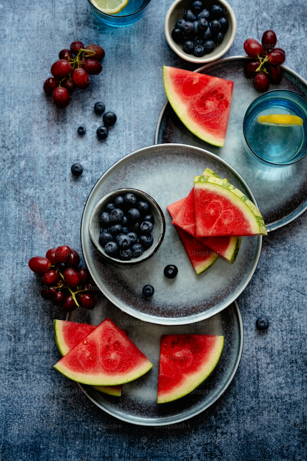 a plate of watermelon slices, blueberries, and grapes