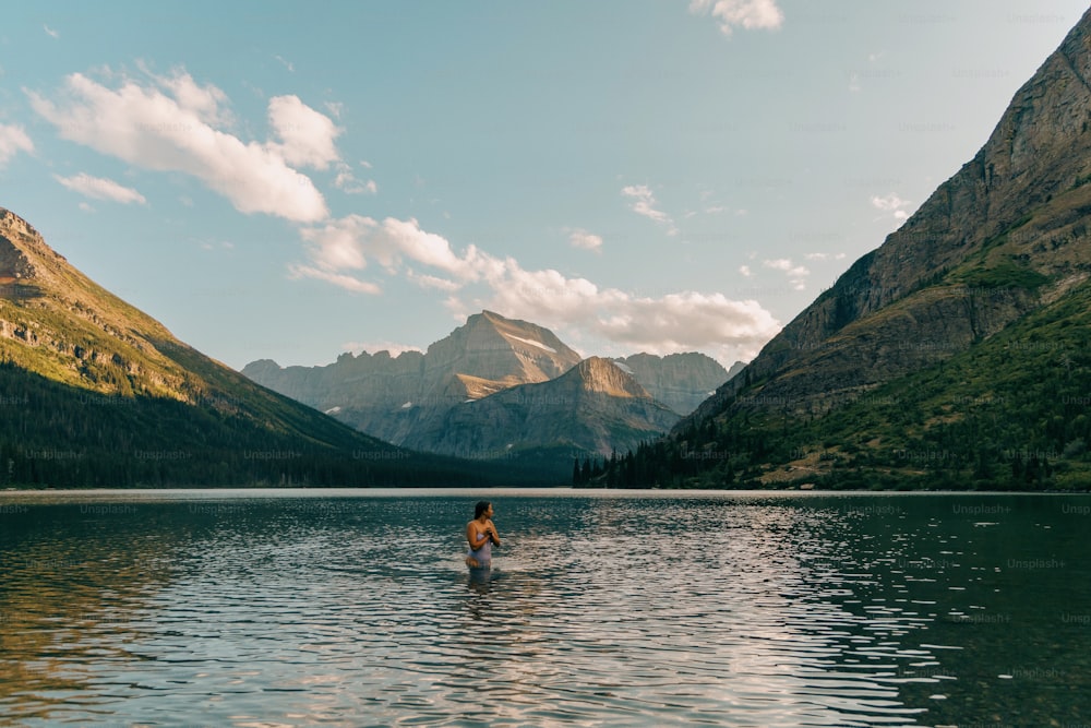 a person wading in a lake with mountains in the background