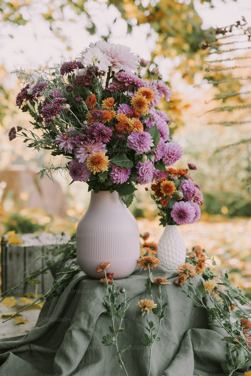 Un jarrón blanco lleno de flores púrpuras y naranjas
