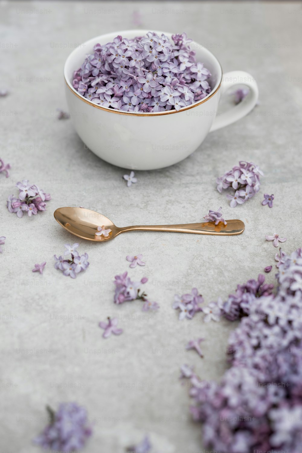 a white bowl filled with purple flowers next to a spoon