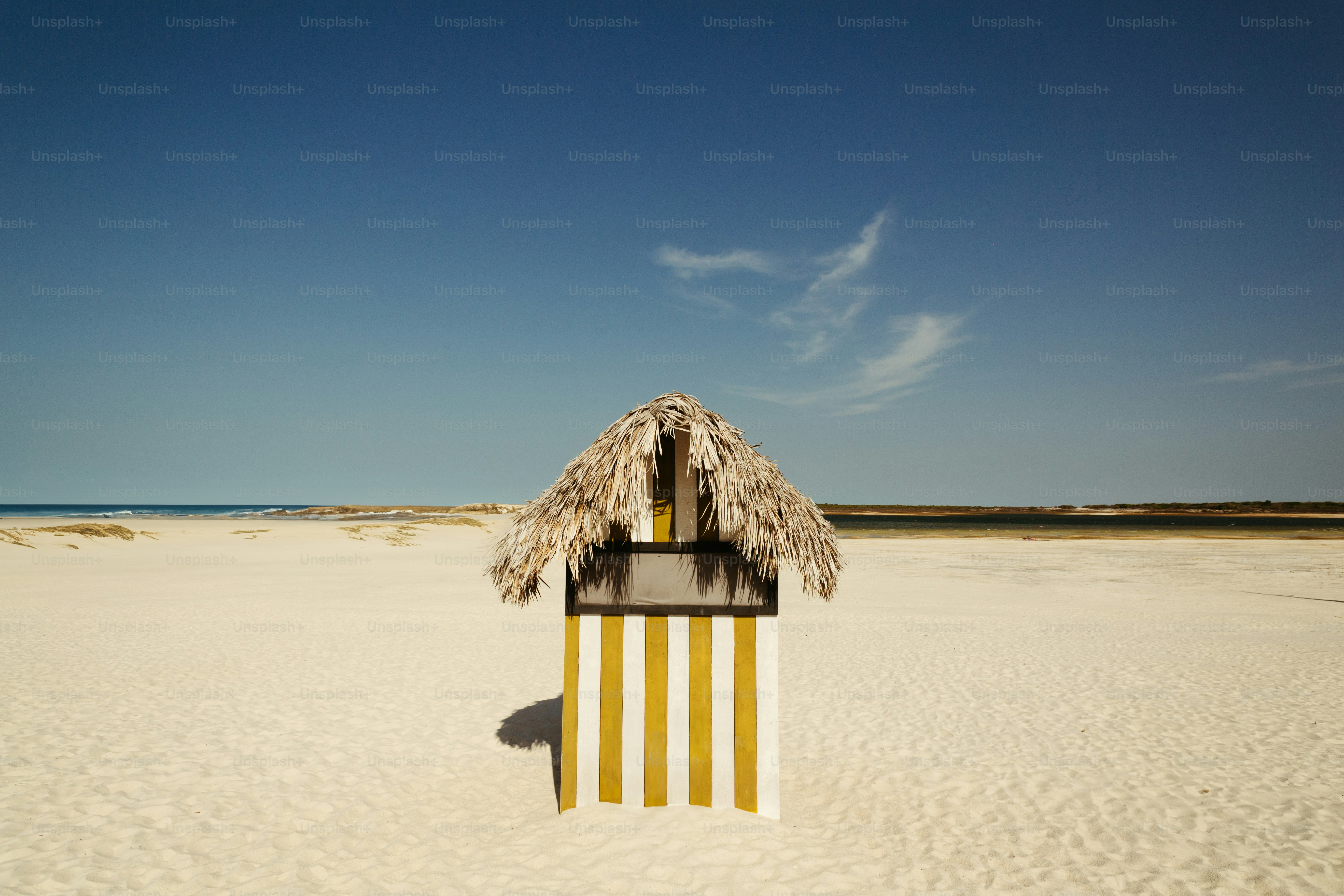 Une cabane tiki sur la plage avec un ciel bleu en arrière-plan