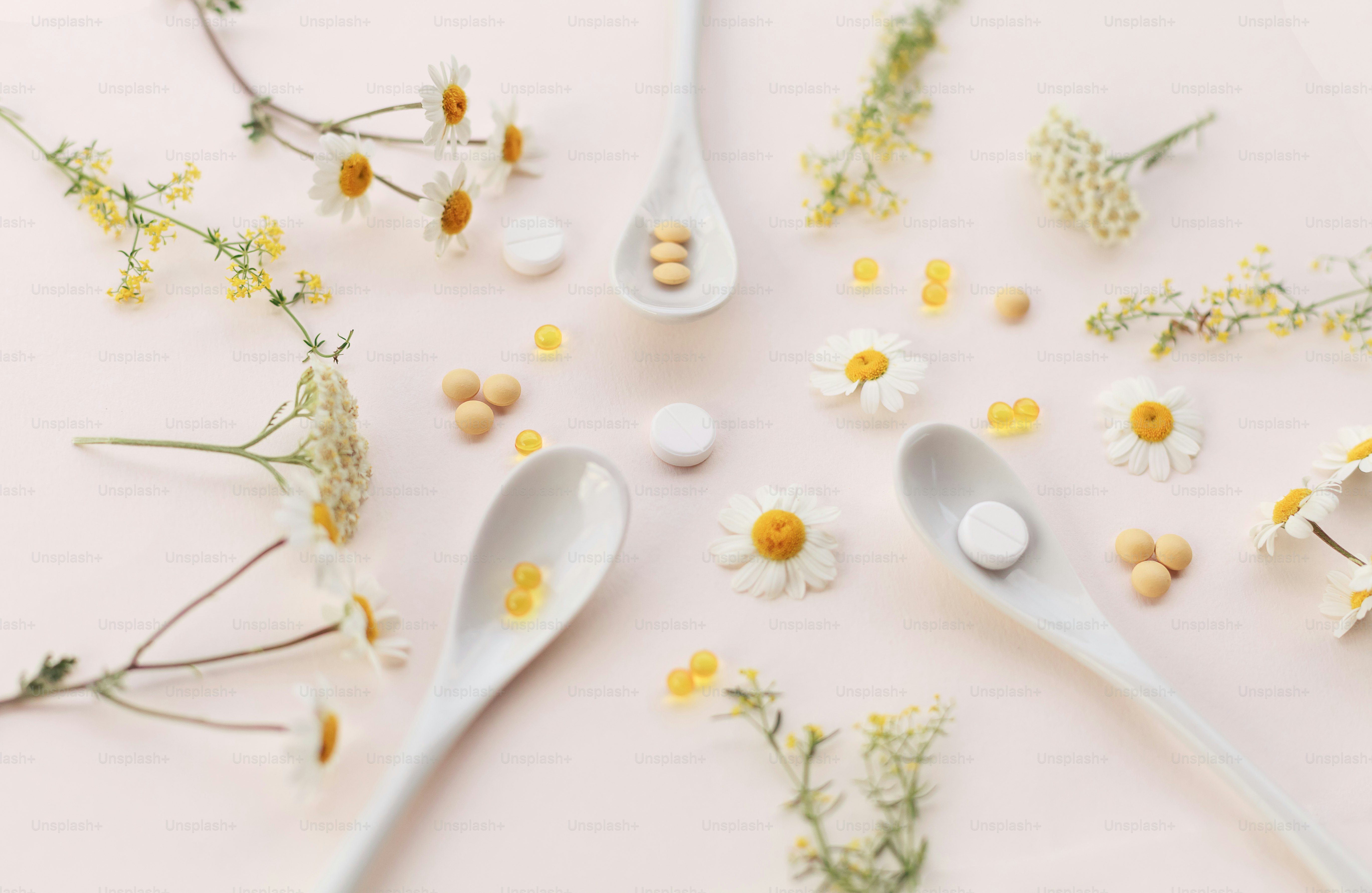 una cuchara con algunas flores y pastillas