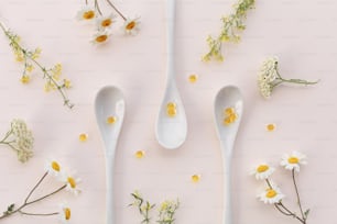 three spoons with flowers on a pink surface