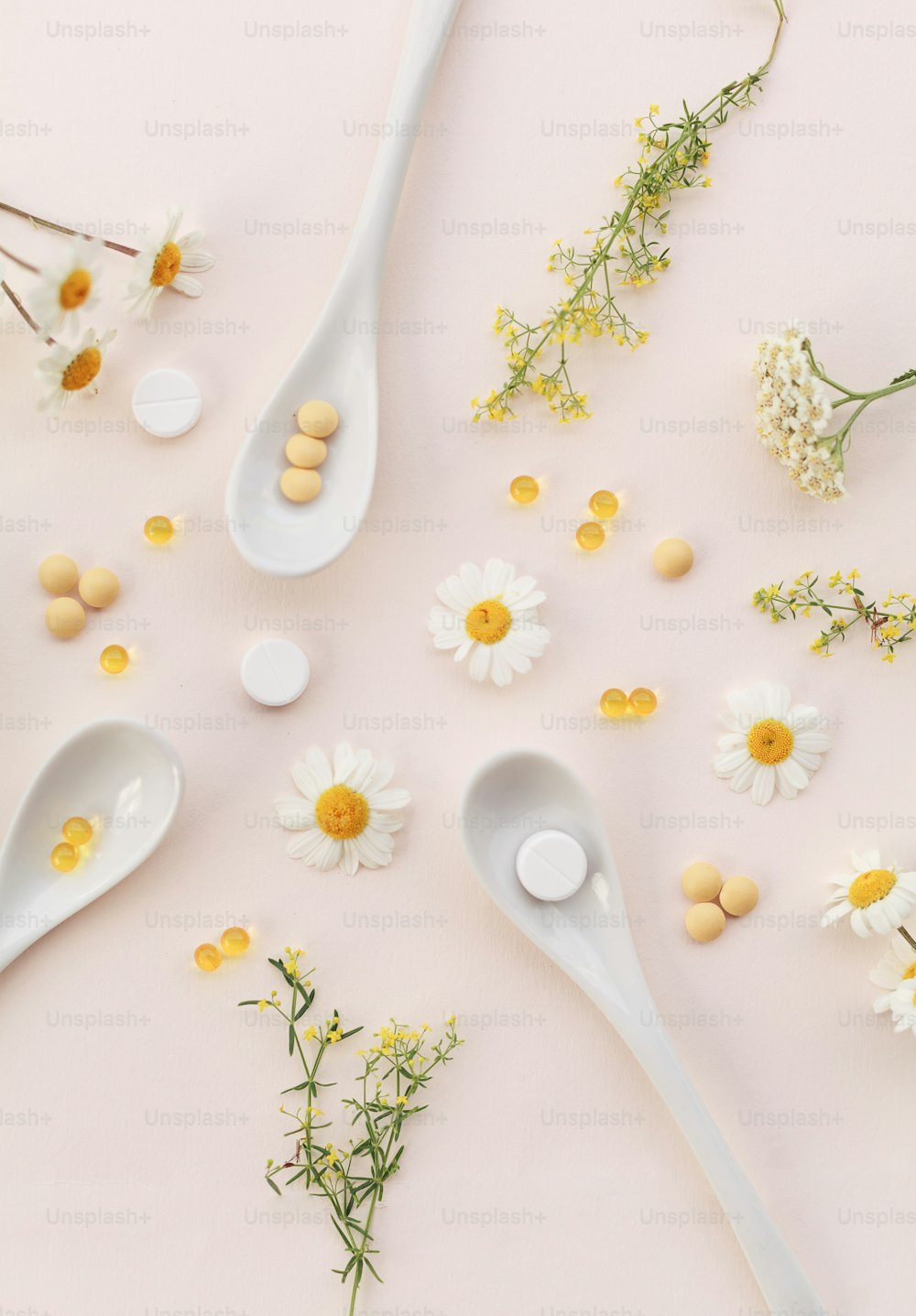 spoons with flowers and pills on a pink surface