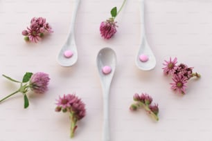 colheres cheias de flores cor-de-rosa em uma superfície branca