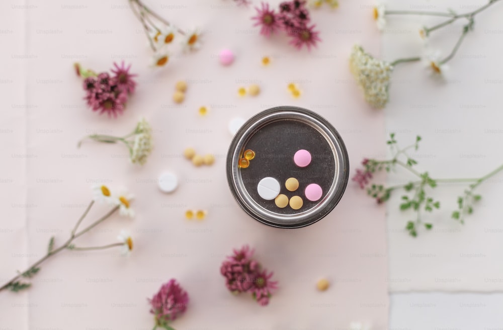 a jar of pills sitting on top of a table next to flowers