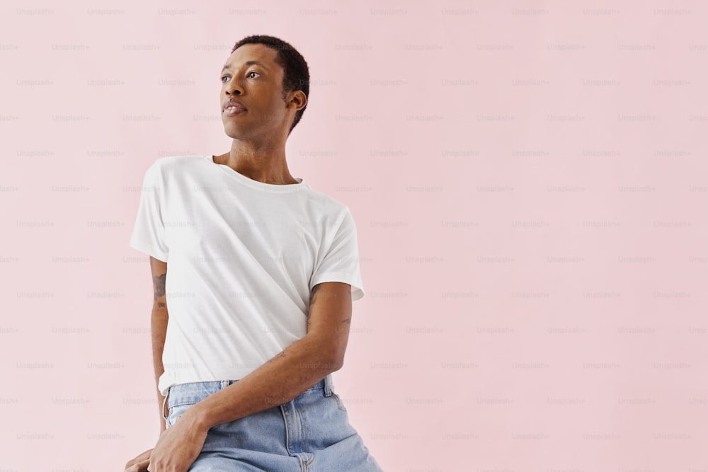 a man in a white t - shirt sitting on a stool